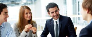 Four colleagues smile and discuss life insurance