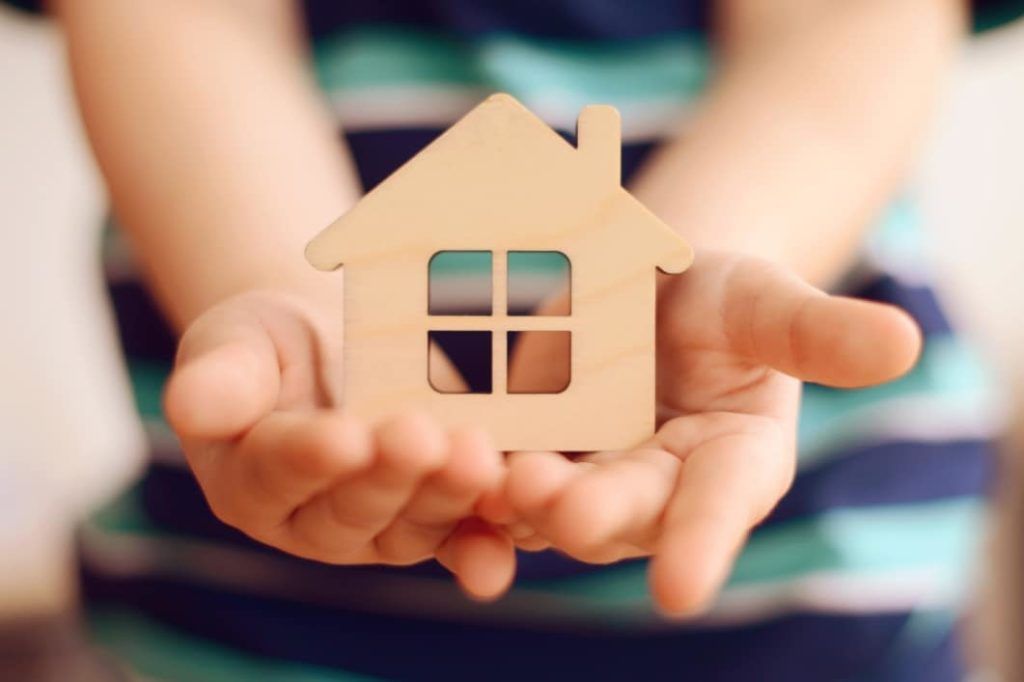 A child holds a small wooden house in their hands