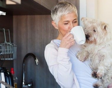 A woman holds her dog and has a drink after securing equity release