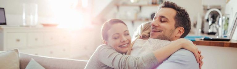 A family smile and embrace after purchasing life insurance