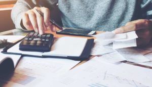 A man looks at bills and a calculator as he considers a debt consolidation loan