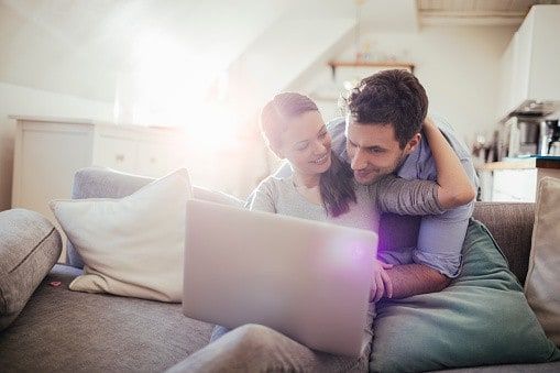 A man and woman embrace as they look at a laptop together and decide to remortgage