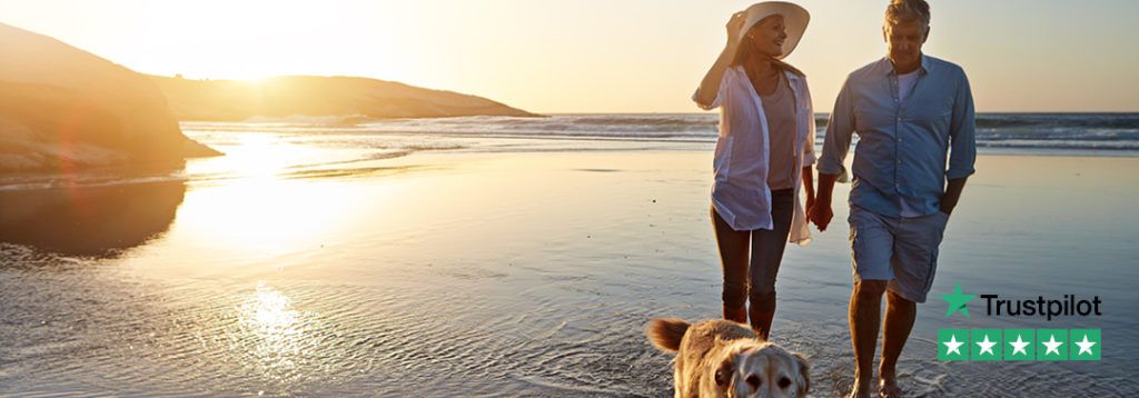 Older couple and a dog enjoy walk on the beach after releasing equity in their home