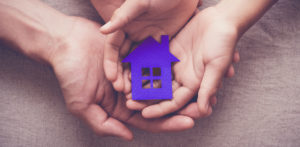 Adult and child hands holding paper house, family home and homeless shelter concept