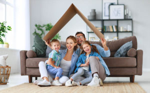 concept of housing and relocation. happy family mother father and kids with roof at home